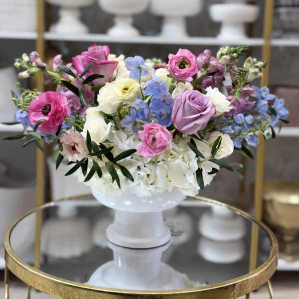 Mixed pastel flower arrangement in a white pedestal vase