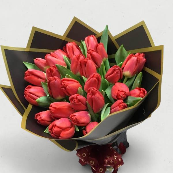 Bouquet of red tulips wrapped in black paper with gold trim