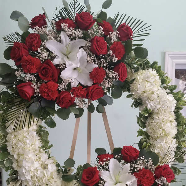 Floral wreath with red roses, white lilies, and white hydrangeas