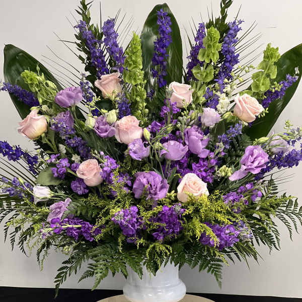 Lavender and pink floral arrangement in a white pedestal vase