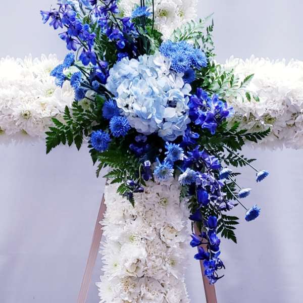 Blue and white floral cross arrangement on a stand