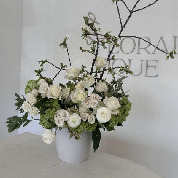 White floral arrangement in a white vase with branching stems
