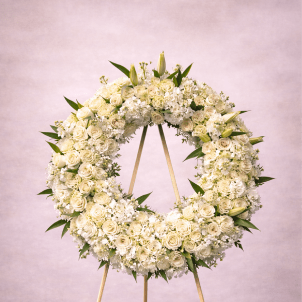 Large white floral wreath on a wooden easel against a soft neutral background