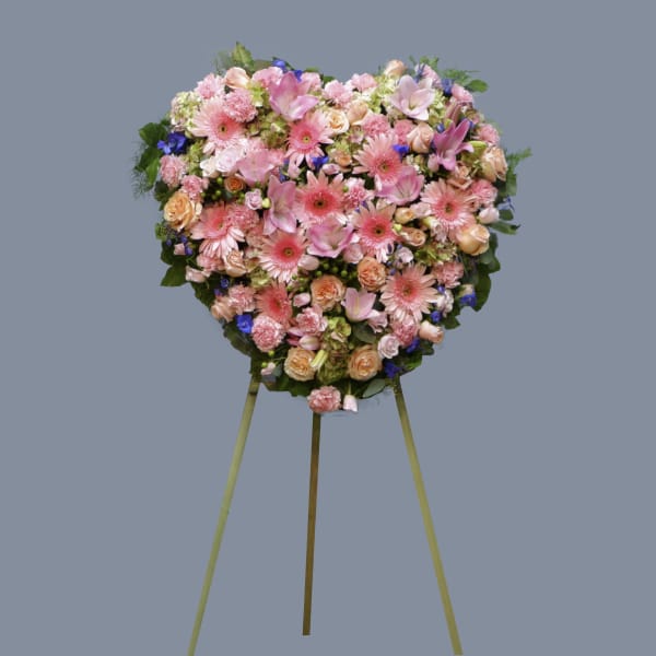 Heart-shaped floral standing spray in pink and peach tones on an easel
