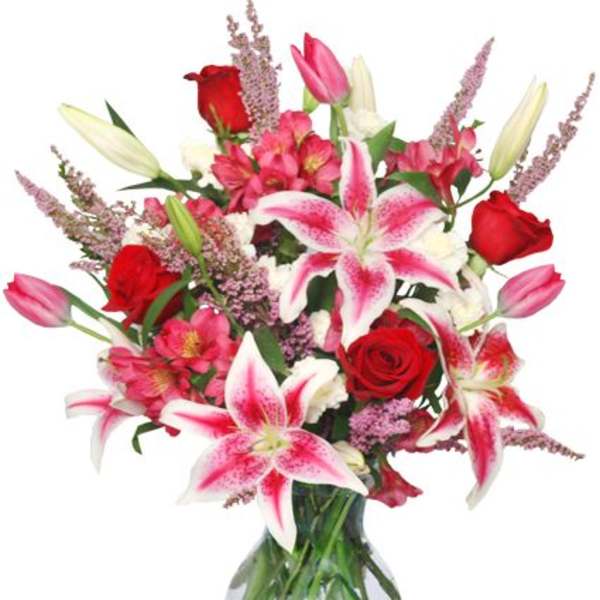 Bouquet of pink lilies and red roses in a glass vase