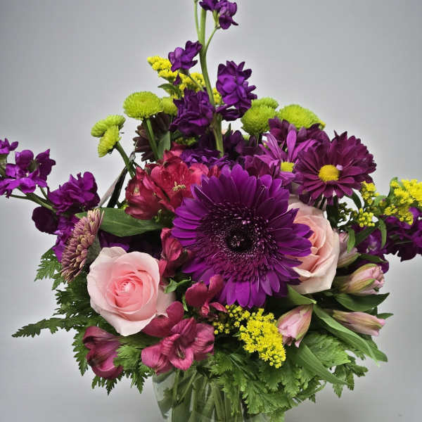 Purple and pink mixed bouquet in a clear glass vase
