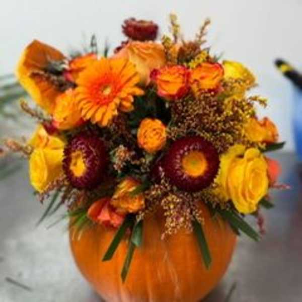 Orange and yellow flower arrangement in a pumpkin container
