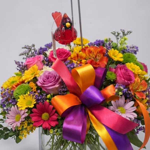 Colorful mixed bouquet with roses, daisies, and a red bird ornament
