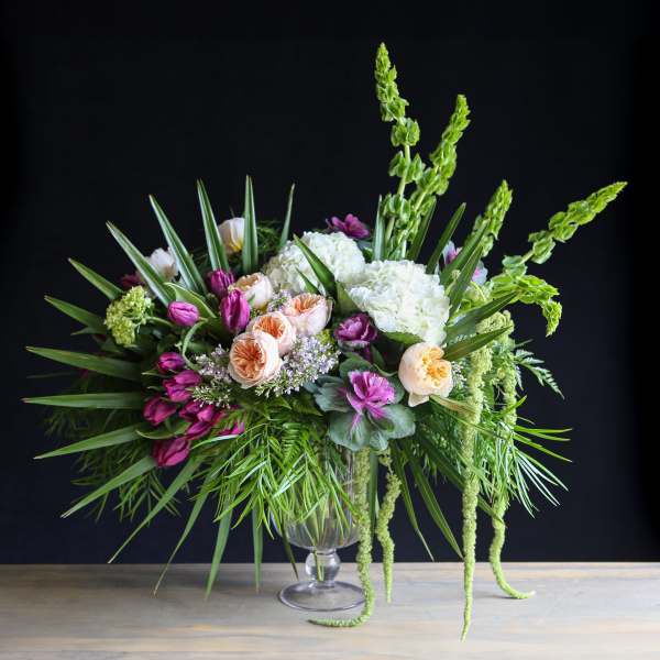 Large mixed floral arrangement in a clear glass vase with pink, white, and peach blooms