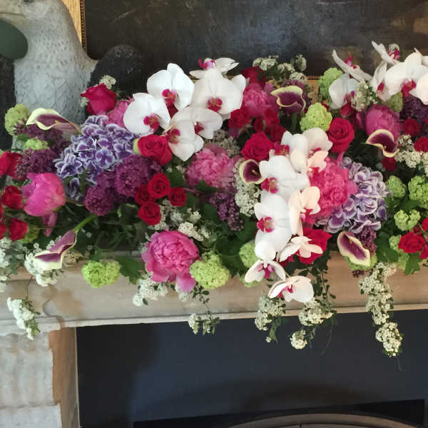 Large floral mantel arrangement with orchids, roses, and hydrangeas