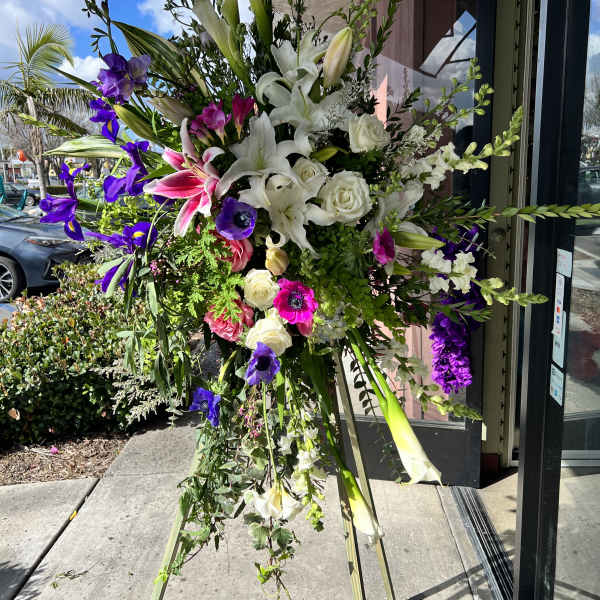 Tall standing floral spray with white lilies, roses, and purple blooms