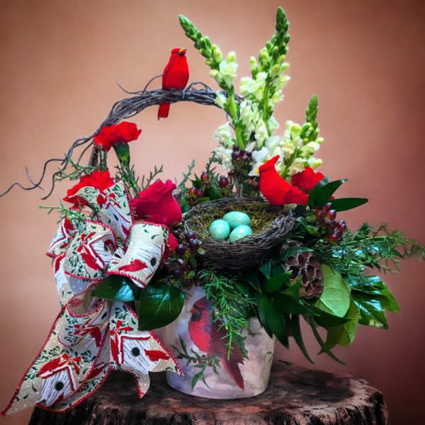 Festive floral arrangement with red flowers, white spikes, and a bird nest centerpiece