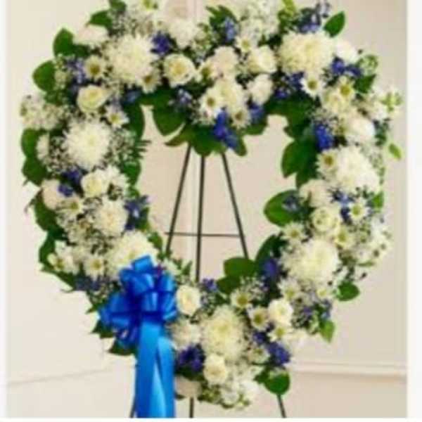 Heart-shaped white floral wreath on an easel with a blue ribbon