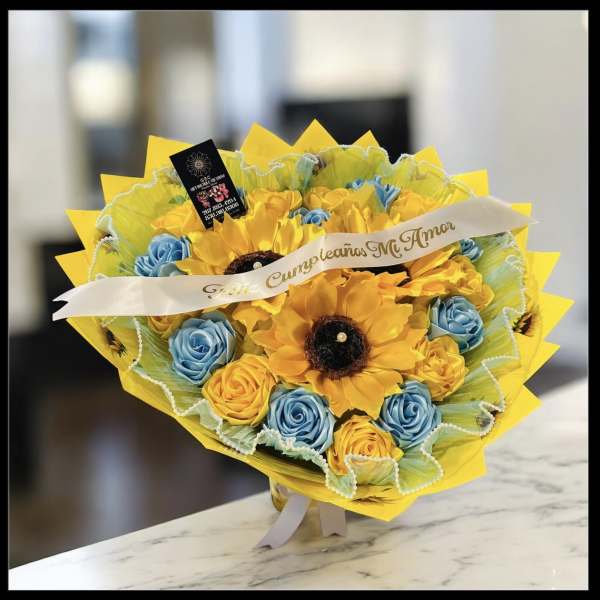 Bouquet of yellow and blue roses with sunflower accents and a ribbon