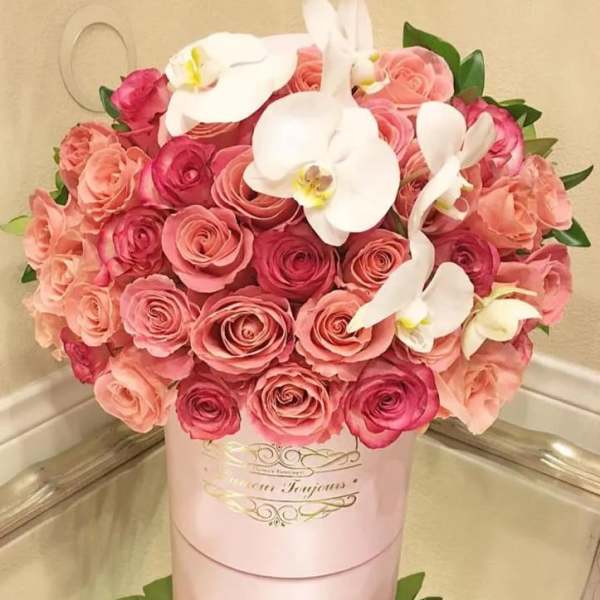 Pink and peach roses with white orchids in a pink hat box