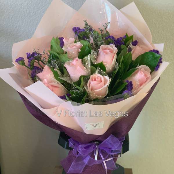 Bouquet of pink roses with purple filler flowers wrapped in pink and purple paper