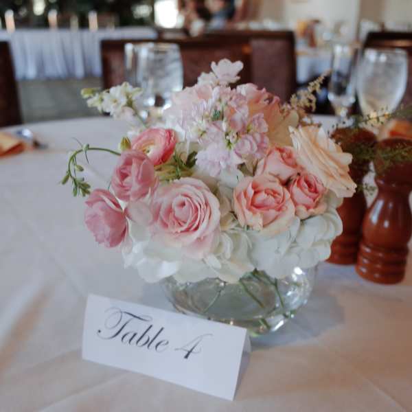 Pink and white floral centerpiece in a glass bowl on a table