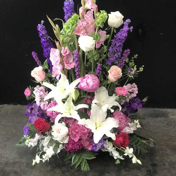 Tall floral arrangement with white lilies, pink roses, and purple blooms