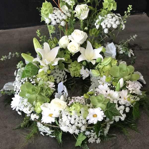 Large white and green floral wreath with roses and lilies
