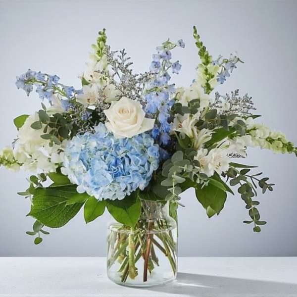 Blue hydrangea and white flower arrangement in a clear glass vase