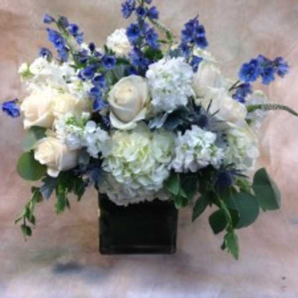 White roses and hydrangeas with blue flowers in a black vase