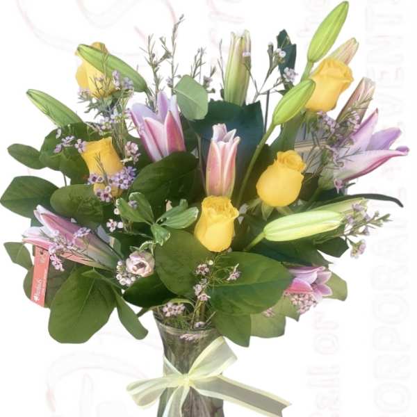 Bouquet of yellow roses and pink lilies in a glass vase