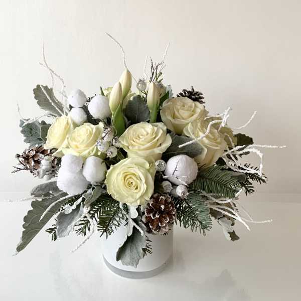 Cream roses and white tulips in a white vase with pinecones and frosted accents