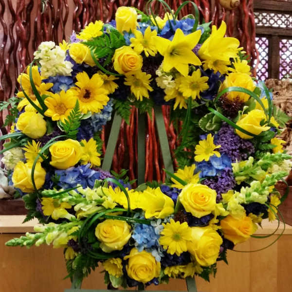 Yellow flower wreath with blue accents on a stand