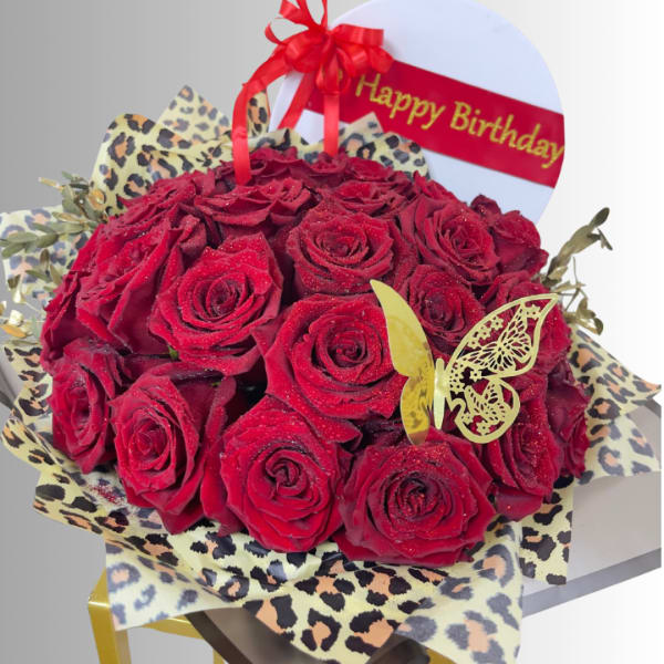 Red rose bouquet with leopard-print wrap and a Happy Birthday topper