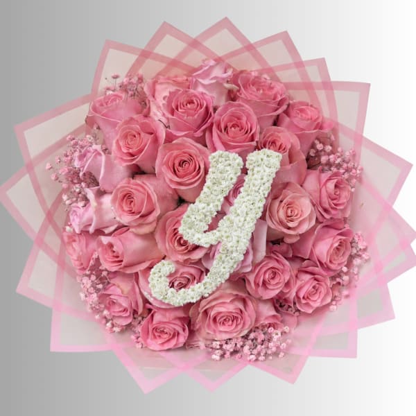 Pink rose bouquet with white floral initials on pink wrap