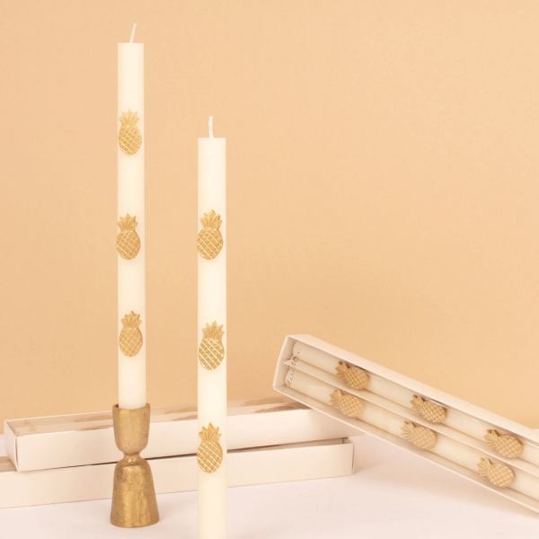 White taper candles with gold pineapple decorations in boxes