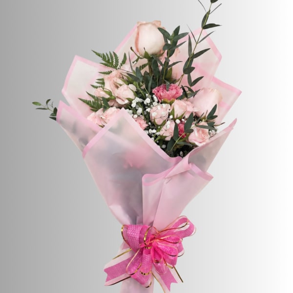 Pink rose bouquet wrapped in translucent pink paper with a ribbon