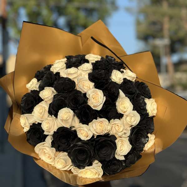 Bouquet of black and cream roses wrapped in gold paper