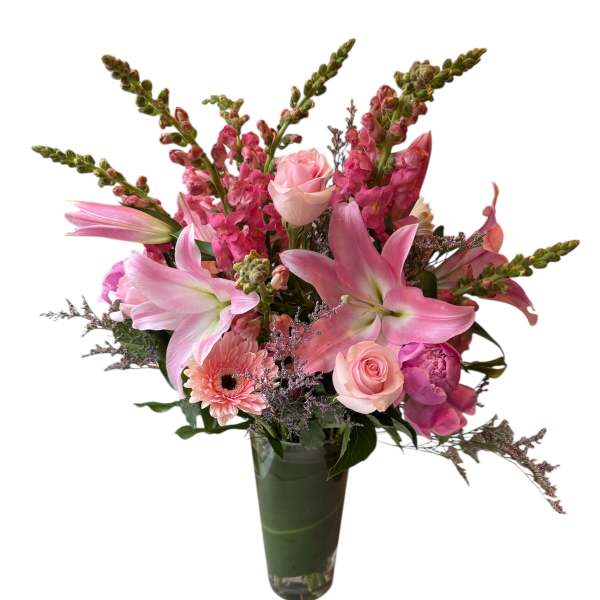 Pink lilies, roses, and snapdragons arranged in a tall glass vase