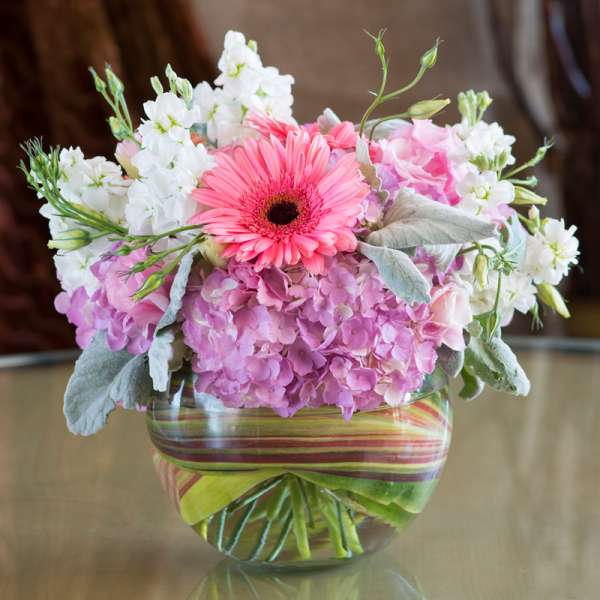 Pink gerbera daisy and hydrangea bouquet in a striped glass vase