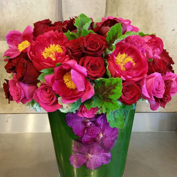 Pink and red flower arrangement in a green glass vase