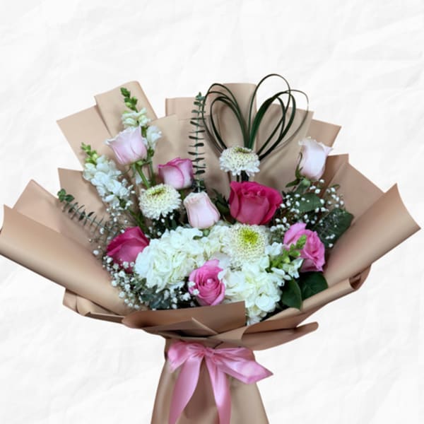 Bouquet of pink and white roses with hydrangeas wrapped in tan paper