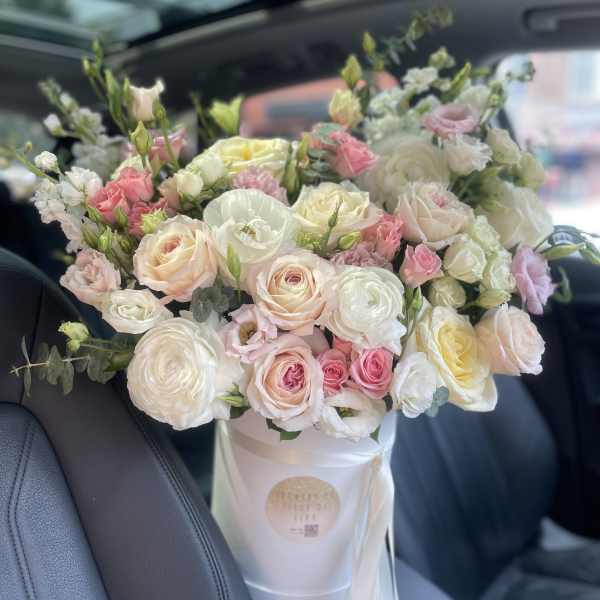 Large bouquet of pale pink, white, and cream roses in a white box