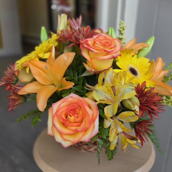 Bouquet of orange-pink roses and yellow flowers in a basket