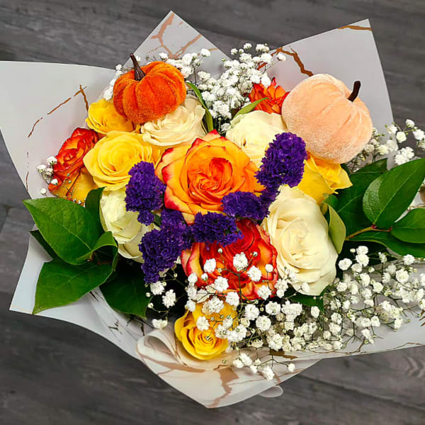 Bouquet of yellow, orange, and white roses with small white filler flowers and plush pumpkins