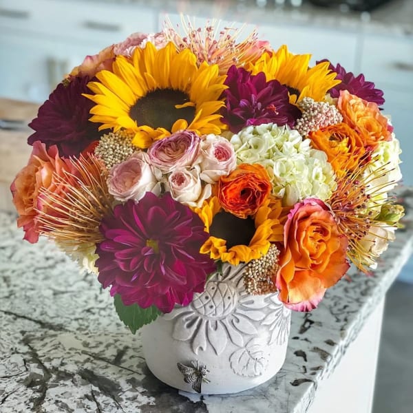 Bright mixed bouquet with sunflowers, dahlias, and roses in a white vase