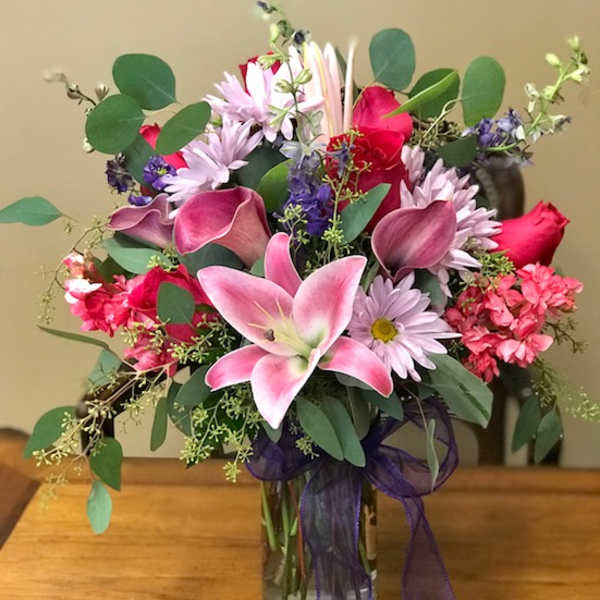 Mixed pink and purple bouquet in a glass vase with a ribbon