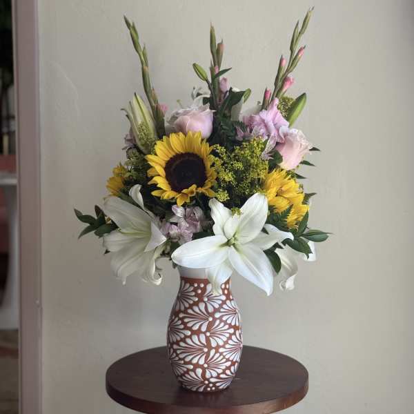 Mixed bouquet with sunflowers and white lilies in a patterned vase