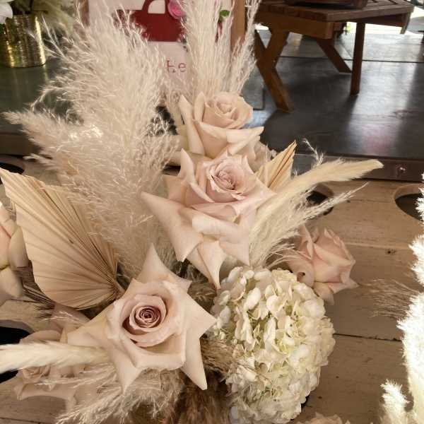 Blush roses and white hydrangea with tall pampas grass in a low arrangement