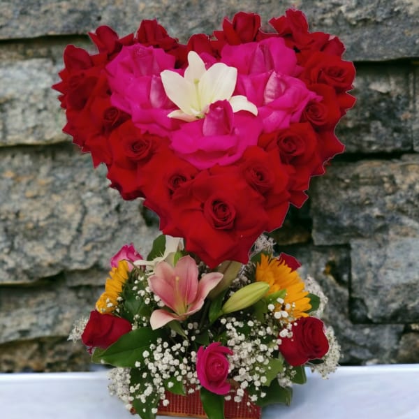 Heart-shaped rose arrangement with lilies and small yellow flowers