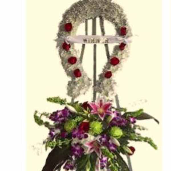Standing funeral wreath on an easel with red roses and purple flowers