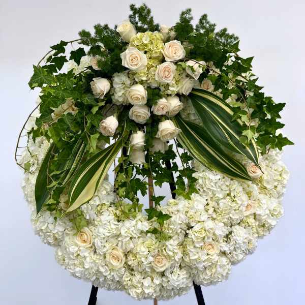 Large white floral wreath with roses and hydrangeas on an easel