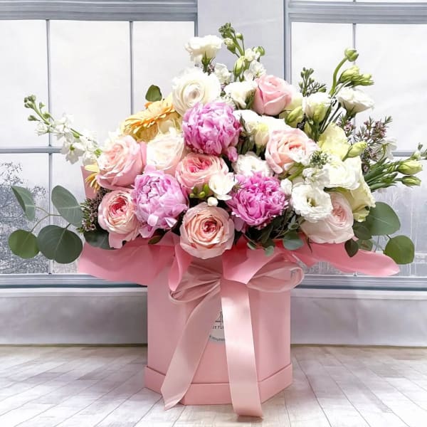Pink and white roses in a pink hat box with a ribbon