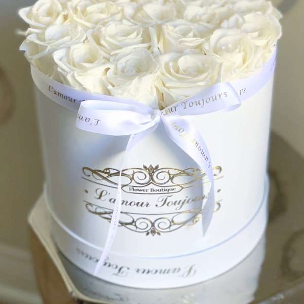White roses arranged in a round white box with a ribbon bow