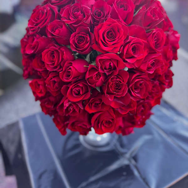 Round bouquet of red roses in a clear vase